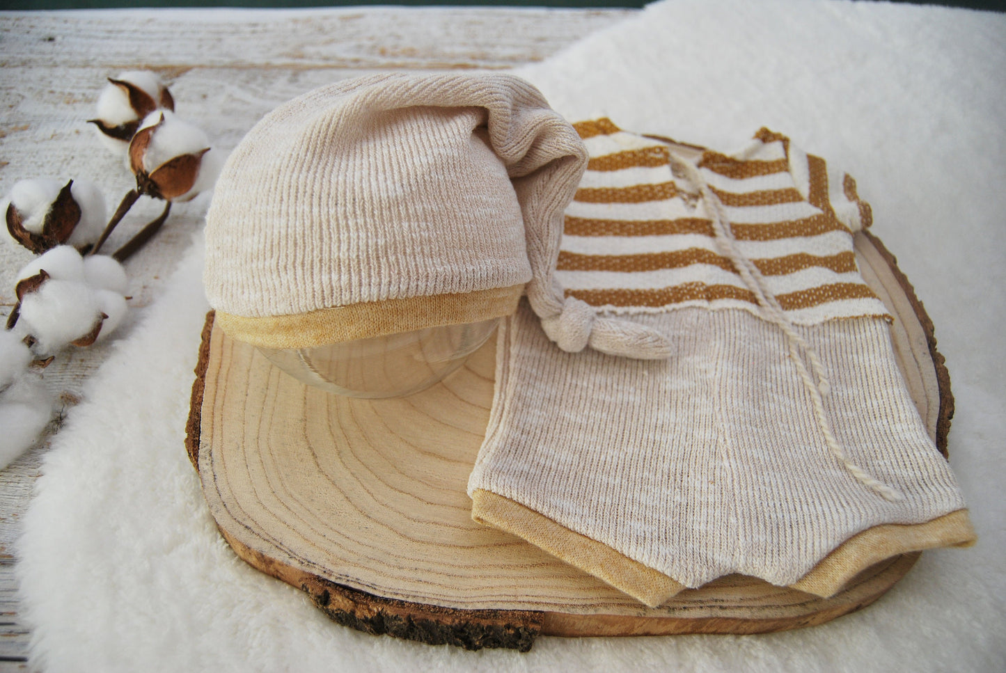 Newborn boy sleepy hat made of knit fabric, in beige color. Matching romper with stripes in mustard and beige. Ideal for newborn photography.