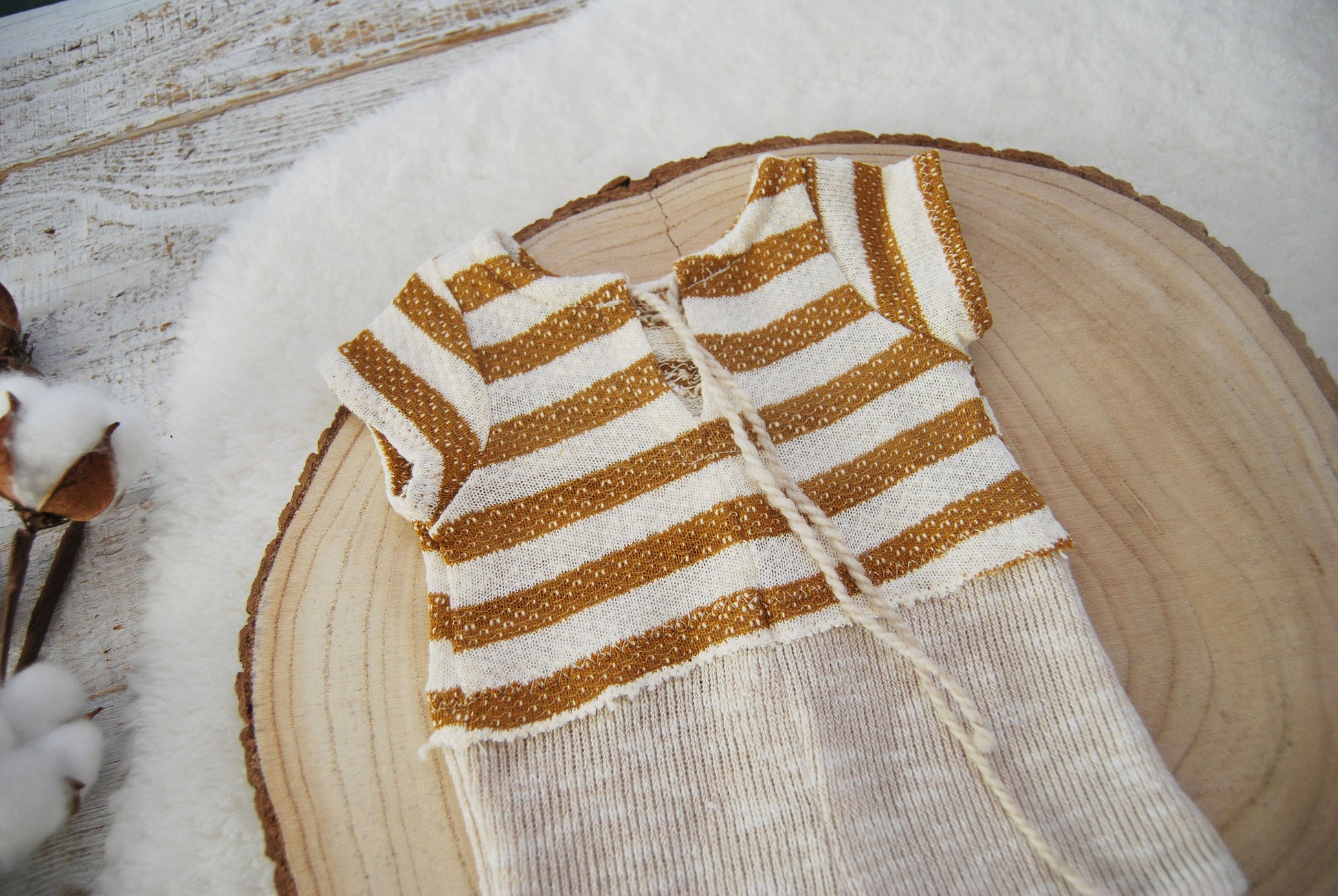 This baby boy photo outfit features an opening on the back. The top part of the romper is made of striped fabric,  while the bottom is plain beige.  Newborn photo prop outfit for baby boys: romper and hat.