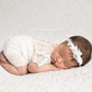 White newborn romper for photo shoots. Made of lace on the top part and stretchy knit fabric for the bottom part. One piece all white baby girl outfit.